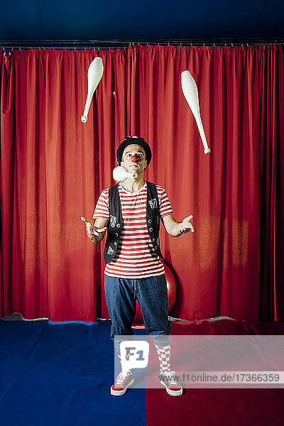 Männlicher Artist jongliert mit Stiften während einer Zirkusvorstellung