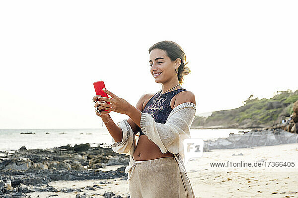 Woman using smart phone while standing at beach