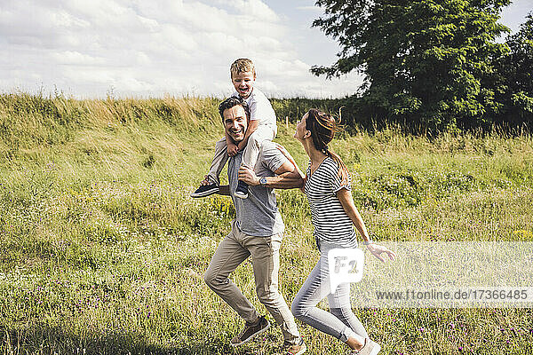 Woman running with family on grass during sunny day