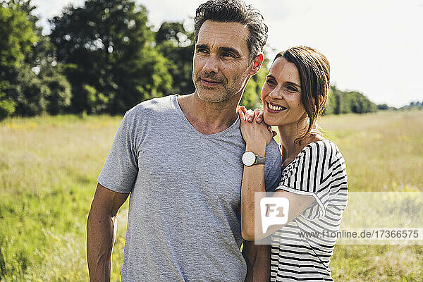 Smiling woman leaning on man's shoulder at meadow