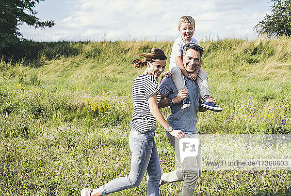 Smiling family running together at meadow