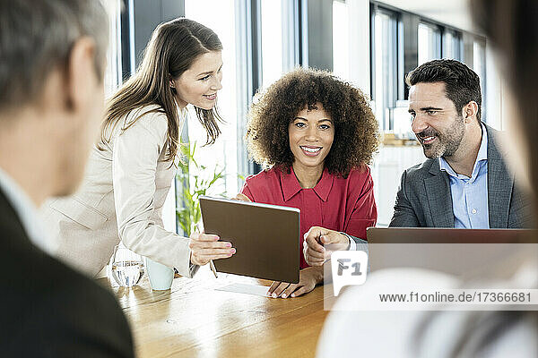 Lächelnde Geschäftsfrau bei einer Besprechung mit Kollegen im Büro