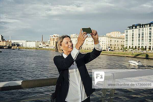 Weibliche Fachkraft nimmt Selfie durch Handy am Fluss