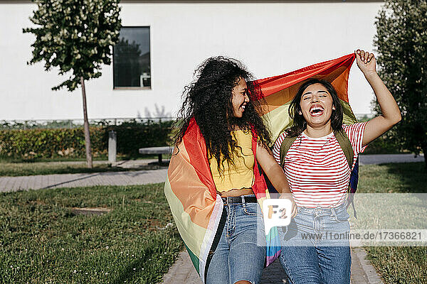 Fröhliche junge Frau sieht lesbische Freundin lachend im Park an