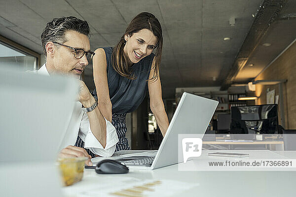 Männliche und weibliche Berufstätige  die einen Laptop bei der Arbeit im Büro benutzen