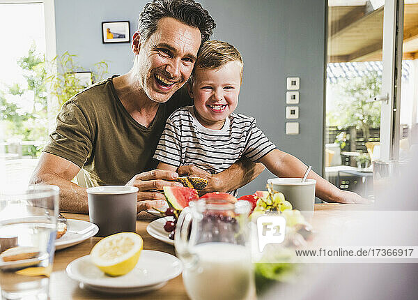 Happy father and son having breakfast at home