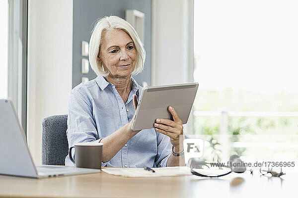 Geschäftsfrau mit digitalem Tablet am Schreibtisch im Heimbüro