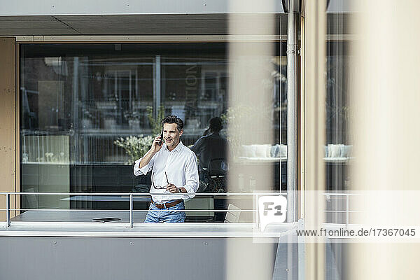 Businessman talking on mobile phone while standing by railing