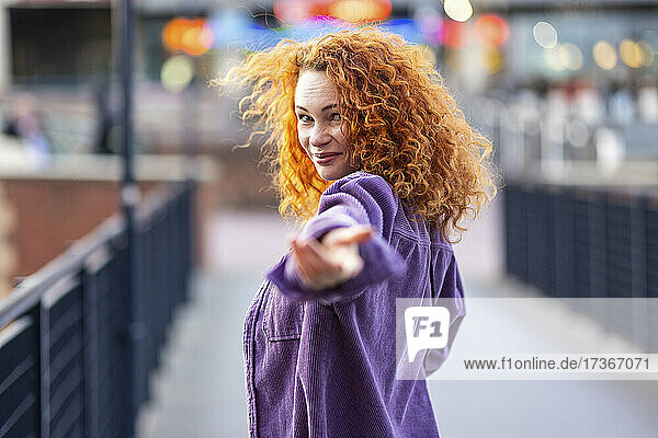 Curly haired woman gesturing while standing on bridge