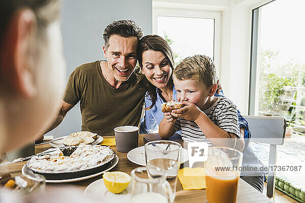 Mann mit Frau sieht Sohn beim Frühstück Kuchen essen