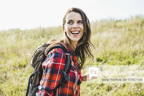 Happy woman with backpack at meadow