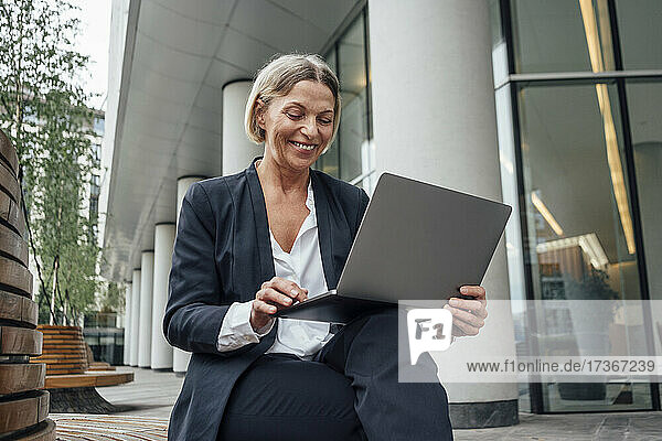 Reife Geschäftsfrau  die im Büropark am Laptop arbeitet