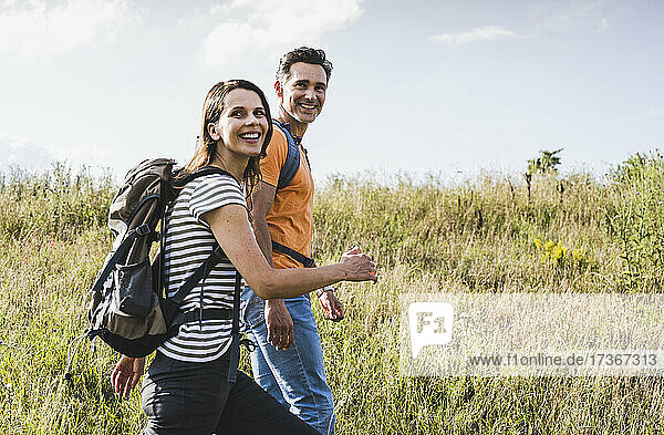 Happy woman hiking with man at meadow
