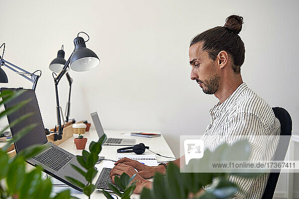 Männlicher Berufstätiger bei der Arbeit am Laptop im Büro