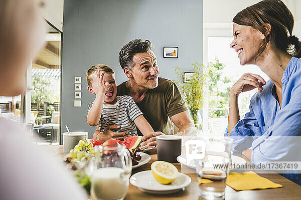 Verspielter Vater und Sohn necken Frau beim Frühstück zu Hause