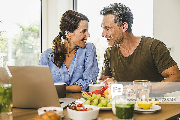 Lächelndes Paar  das sich beim Frühstück zu Hause gegenseitig ansieht