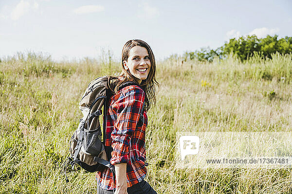Female hiker smiling while looking over shoulder on sunny day