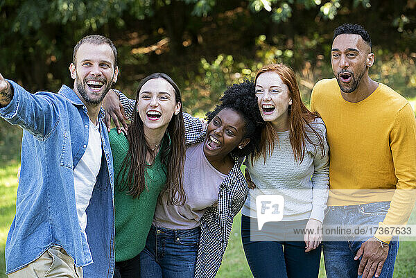Lächelnder junger Mann  der auf die Entfernung für eine Gruppe von Freunden zeigt