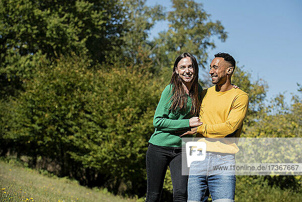 Lächelndes junges Paar beim Spaziergang in einem öffentlichen Park