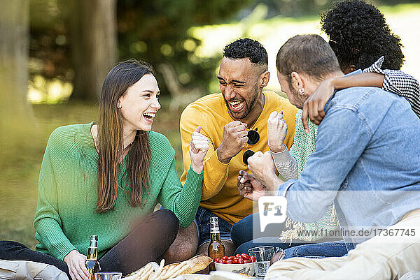 Glückliche junge Freunde beim Picknick im öffentlichen Park