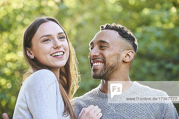 Lächelndes junges Paar im öffentlichen Park sitzend
