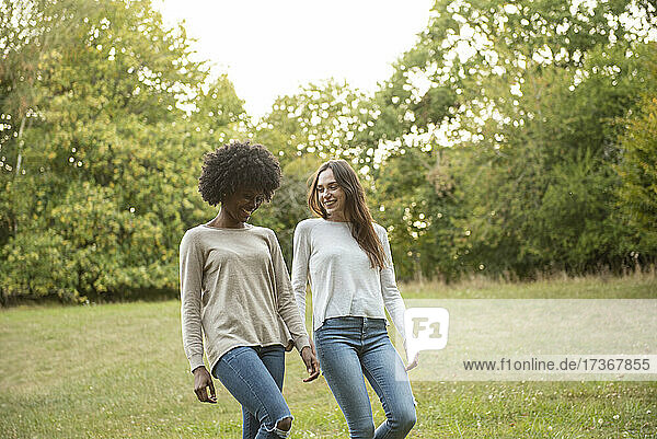 Smiling young female friends walking in park