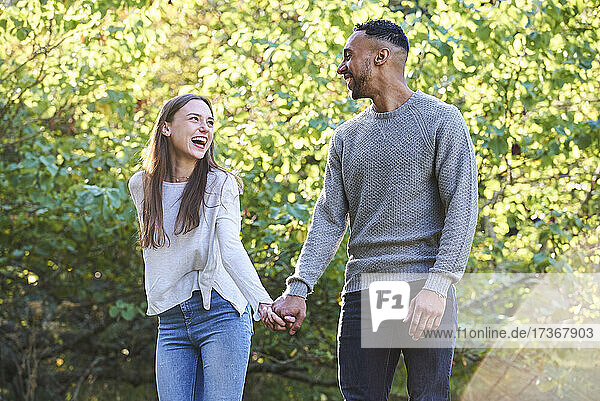 Lächelndes junges Paar  das sich im öffentlichen Park ansieht