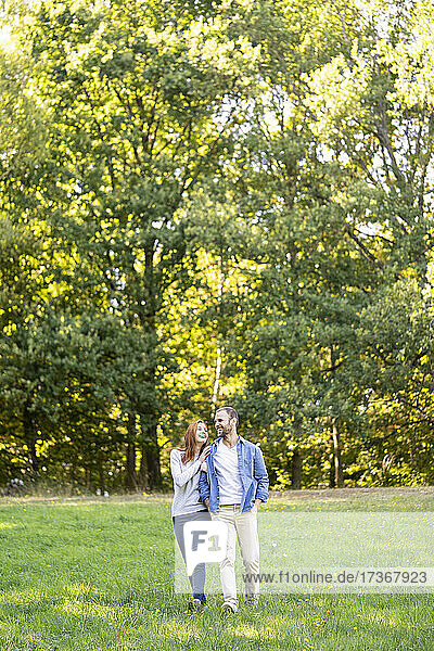 Lächelndes junges Paar hat Spaß beim Spaziergang im Park