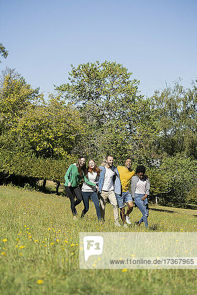 Glückliche junge Freunde haben Spaß beim gemeinsamen Spaziergang im Park