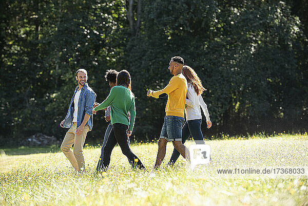 Glückliche junge Freunde  die zusammen in einem öffentlichen Park spazieren gehen