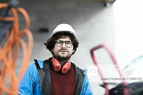Junger Ingenieur mit Helm und Hörschutz checkt Arbeitstelle außen  Freiburg  Baden-Württemberg  Deutschland  Europa