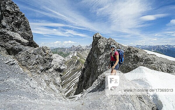 Wanderin an einem Felsen beim Aufstieg auf den Gipfel Mädelegabel  Heilbronner Weg  Allgäuer Alpen  Allgäu  Bayern  Deutschland  Europa