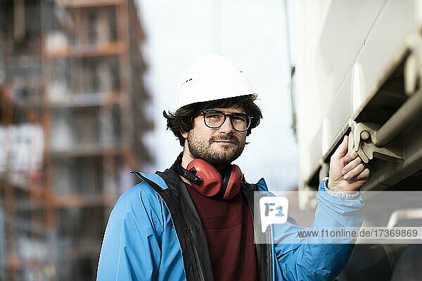 Young engineer wearing a helmet and hearing protection at a work site outside on a construction site  Freiburg  Baden-Württemberg  Germany  Europe