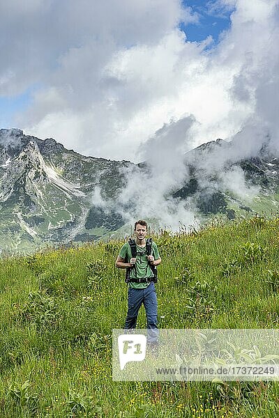 Junger Mann  Wanderer in einer Wiese  hinten Berggipfel  Abstieg von der Rappenseehütte  Allgäuer Alpen  Allgäu  Bayern