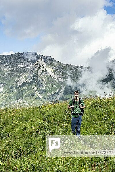 Junger Mann  Wanderer steht in einer Wiese  hinten Berggipfel  Abstieg von der Rappenseehütte  Allgäuer Alpen  Allgäu  Bayern