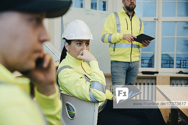 Nachdenkliche Bauunternehmerin  die während einer Besprechung mit einem digitalen Tablet im Büro sitzt