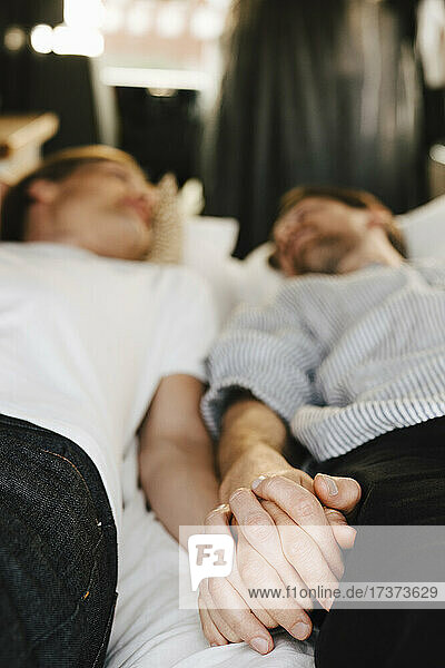Gay couple holding hands while lying down in motor home during vacation