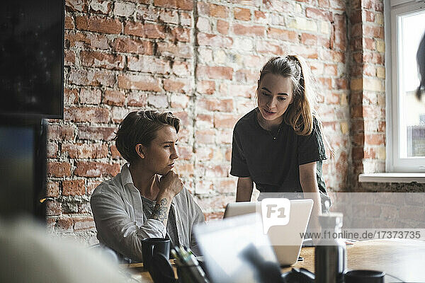 Businesswoman discussing with female colleague over laptop at office