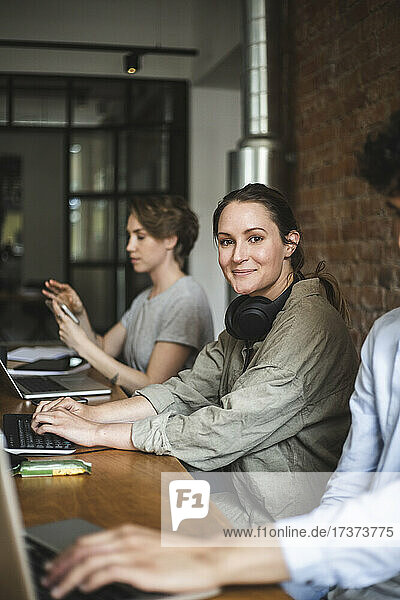 Portrait of female hacker sitting with colleagues in office