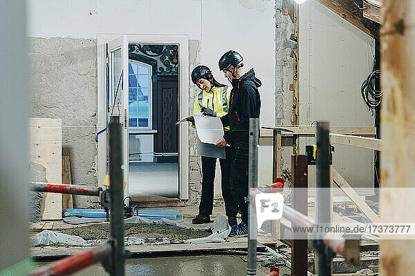Weiblicher Ingenieur diskutiert mit männlichem Bauarbeiter auf der Baustelle