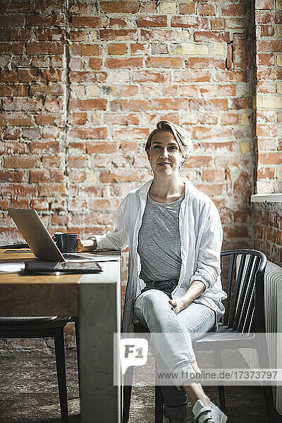 Porträt eines weiblichen Hackers  der auf einem Stuhl im Büro sitzt