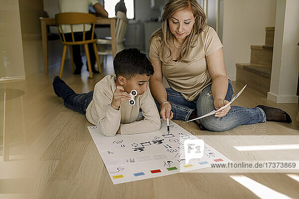 Mutter unterrichtet autistischen Sohn im Wohnzimmer sitzend