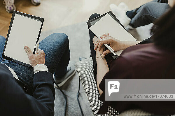 Hochformatige Ansicht einer Unternehmerin und eines Unternehmers mit digitalem Tablet im Unterricht