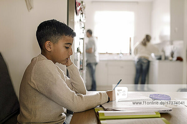 Autistischer Junge schreibt zu Hause über dem Tisch in ein Buch