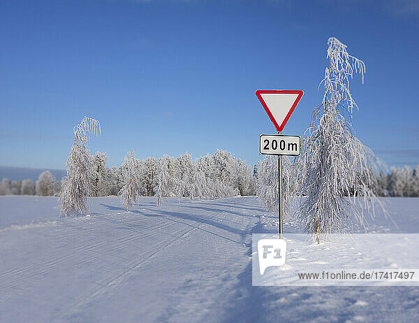 Verkehrszeichen am Straßenrand im Winter. Verkehrszeichen Vorfahrt gewähren oder Vorfahrt gewähren .