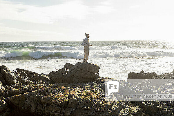 Teenage girl standing looking out to sea  surf rolling into the shore.