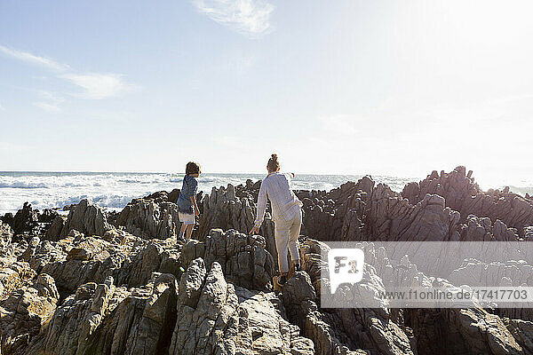 Two children exploring the jagged rocks and rock pools on the Atlantic Ocean coastline