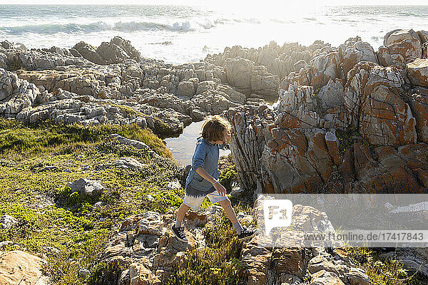 Boy exploring the jagged rocks and rock pools on the Atlantic Ocean coastline