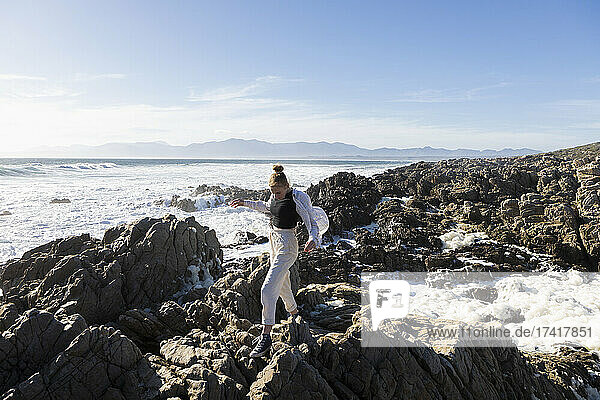 Teenage girl exploring the jagged rocks and rock pools on the Atlantic Ocean coastline