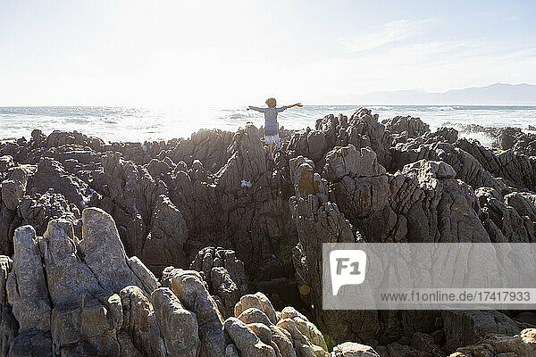 Boy exploring the jagged rocks and rock pools on the Atlantic Ocean coastline